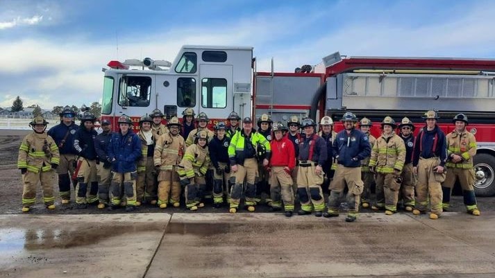 firefighters standing in front of a fire engine